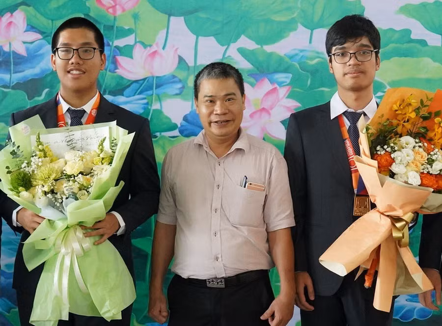 Thầy Lê Công Lợi - Hiệu trưởng Trường THPT chuyên Khoa học Tự nhiên tặng hoa chúc mừng Phạm Công Minh và Hoàng Xuân Bách. Ảnh: NTCC
