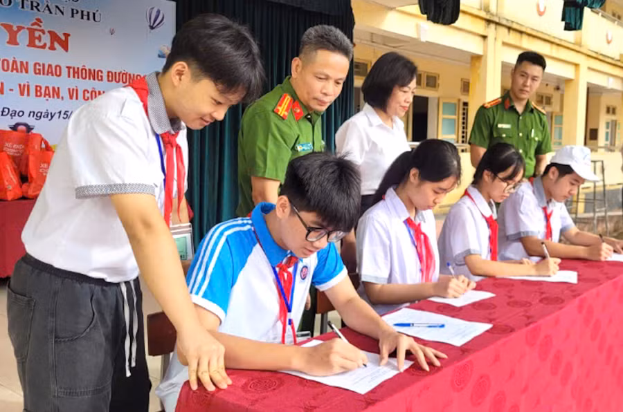 Học sinh Trường THCS Trần Phú (phường Trần Hưng Đạo) ký cam kết tại buổi ngoại khóa tuyên truyền pháp luật về bảo đảm trật tự, an toàn giao thông và kỹ năng sử dụng mạng xã hội an toàn.