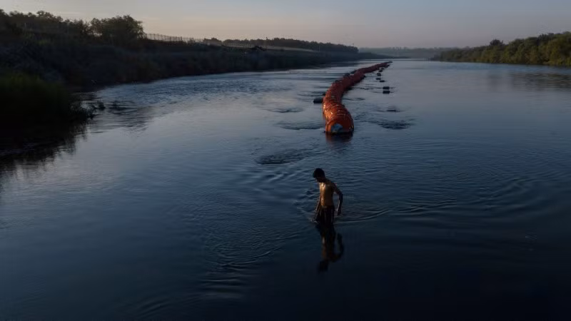Một đối tượng đưa người di cư trái phép đi qua phao ngăn người di cư trên sông Rio Grande giữa Mỹ và Mexico, ở Eagle Pass, Texas, Mỹ. Ngày 14/9/2023. Chùm ảnh tuyến đường di cư nguy hiểm nhất thế giới