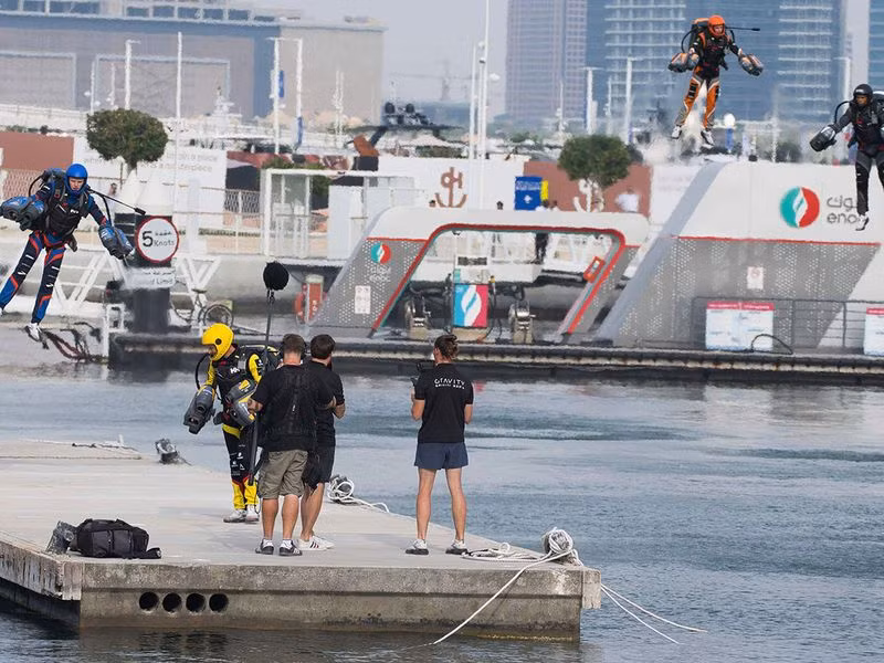 Các tay đua chạy dọc theo một tuyến đường với những tòa nhà chọc trời của Dubai Marina thấp thoáng phía sau, điều khiển động cơ phản lực trên tay và lưng. Chùm ảnh cuộc thi của các Iron Man ở Dubai