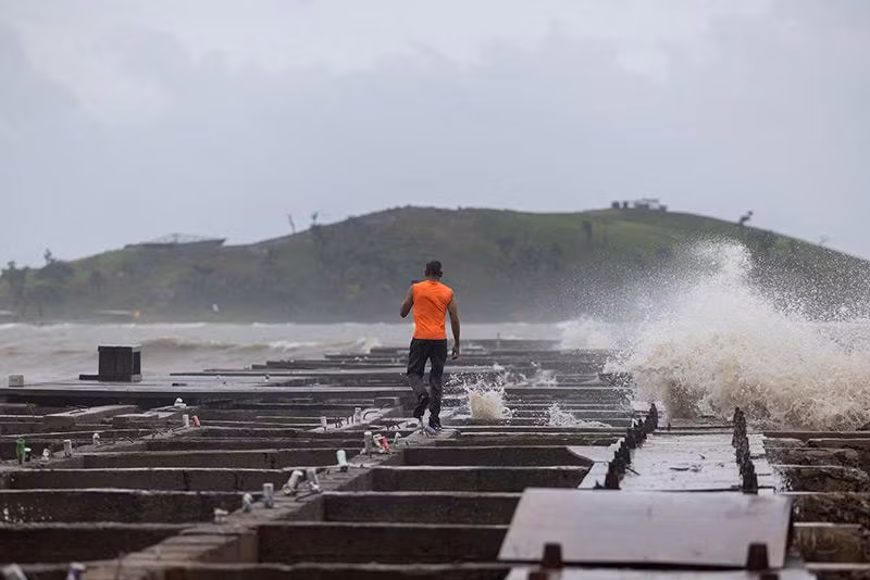 Một người đi bộ khi sóng đánh vào một cầu tàu bị hư hại sau cơn bão nhiệt đới Ernesto ở Humacao, Puerto Rico. khac-phuc-hau-qua-sau-bao-nhiet-doi-puerto-rico-03.jpg