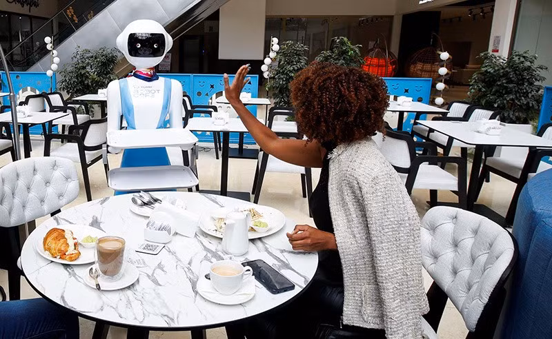 Caroline Nyaga phản ứng sau khi nhân viên phục vụ công nghệ Robot giao đơn đặt hàng bữa ăn của cô tại Robot Cafe, trung tâm ẩm thực có robot phục vụ khách hàng tại Nairobi, Kenya, ngày 22/8. Ảnh: REUTERS su-troi-day-cua-robot-06-1334.jpg
