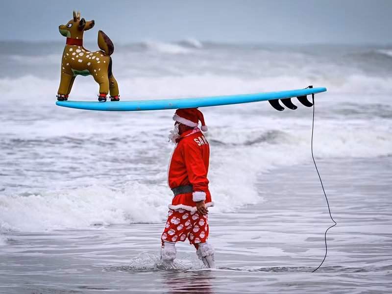 Một người lướt sóng hóa trang thành Ông già Noel tham gia sự kiện "Ông già Noel lướt sóng" thường niên lần thứ 16 vào đêm Giáng sinh tại Cocoa Beach, Florida, Mỹ ngày 24/12. Ảnh: AFP top-10-nhung-hinh-anh-an-tuong-nhat-trong-tuan-12.jpg
