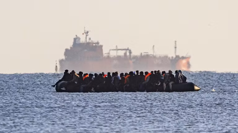 Xuồng nhỏ chở người di cư hướng về Dover, phía sau là một tàu chở hàng rời, gần Calais, Pháp, ngày 6/9/2026.