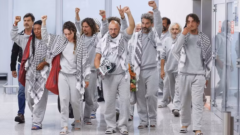 Các nhà hoạt động của Đoàn tàu Sumud toàn cầu, mặc đồng phục tù nhân Israel, khi họ đến Rome, Ý. 