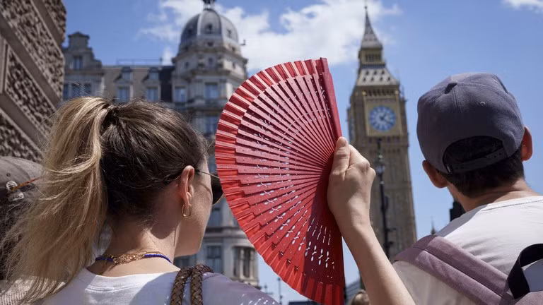 Du khách dùng quạt trước tòa nhà Quốc hội trong đợt nắng nóng ở London, Anh, ngày 19/6/2026.