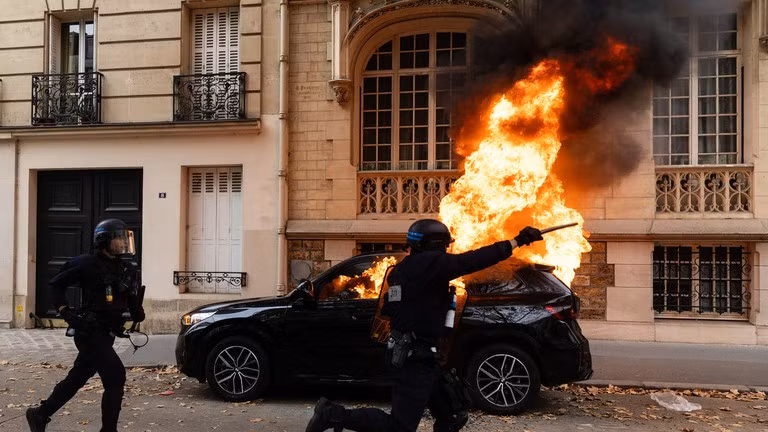Một chiếc xe bốc cháy trong cuộc biểu tình quy mô lớn tại Place d'Italie ở Paris, Pháp, ngày 13/10/2026. 