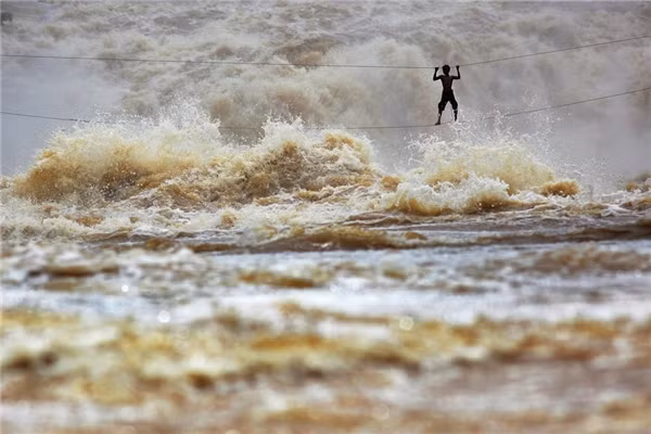 Vào mùa mưa, ông Samnieng - một ngư dân Lào - tự chế một cây cầu từ hai sợi dây chắc để băng qua sông Mekong tại tỉnh Champasak, Lào.&nbsp;
