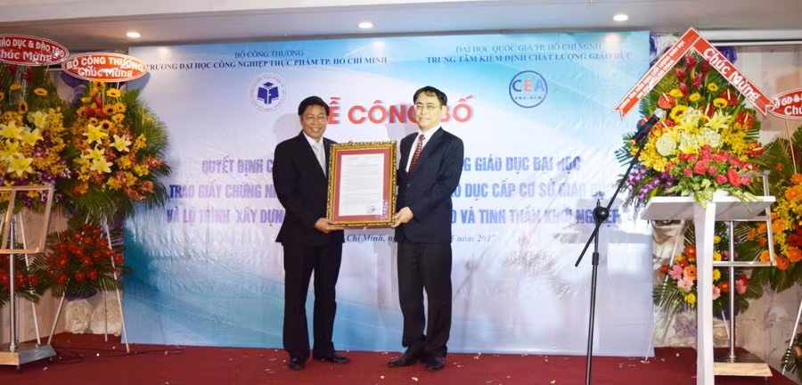 PGS.TS Nguyễn Xuân Hoàn nhận chứng nhận đạt kiểm định chất lượng từ PGS.TS Nguyễn Hội Nghĩa - Giám đốc Trung tâm kiểm định chất lượng giáo dục ĐHQG TPHCM