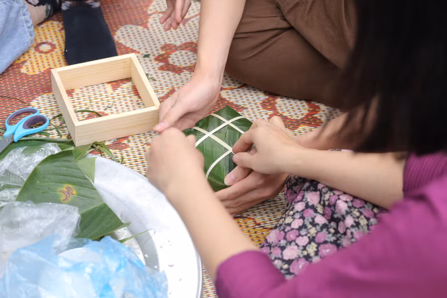 Học sinh cùng gói bánh chưng với phụ huynh tại trường.