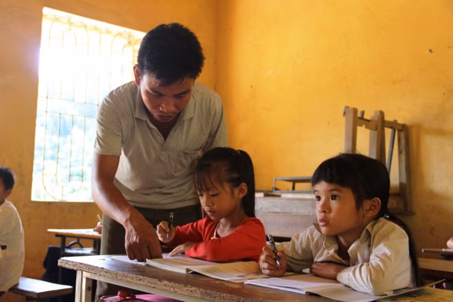 Đón trò vào lớp, còn con mình đành trông chờ người thân. Ảnh: T.G