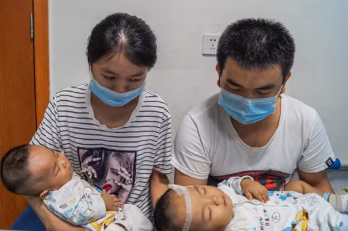 Cặp sinh đôi Kangkang và Lele 10 tháng tuổi bênbố mẹ. Cặp sinh đôi 10 tháng tuổi và bố mẹ. Ảnh: Quỹ Từ thiện Trẻ em Trung Quốc.