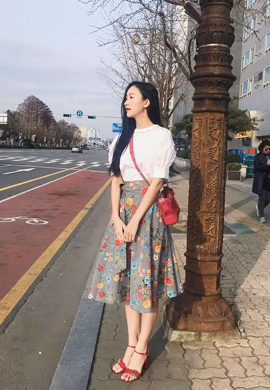Chân váy midi rực rỡ sắc hoa được Hà Thu kết hợp ăn ý cùng túi đeo chéo hàng hiệu, sandal quai mảnh và áo trắng tây bồng hợp mốt.