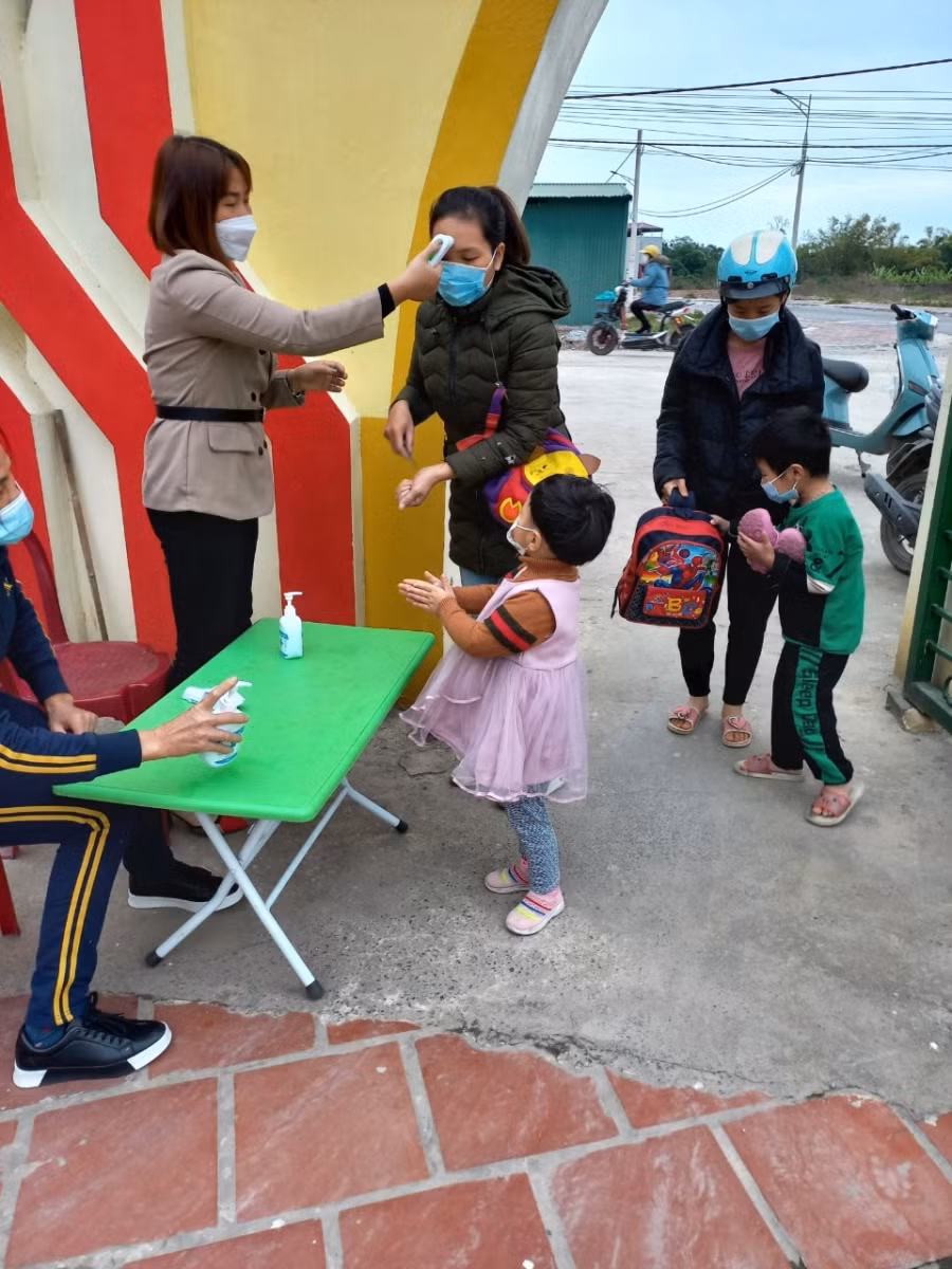 Phụ huynh và học sinh khi đến trường đều được đo thân nhiệt, yêu cầu rửa tay sát khuẩn. Ảnh: Khôi Nguyên.