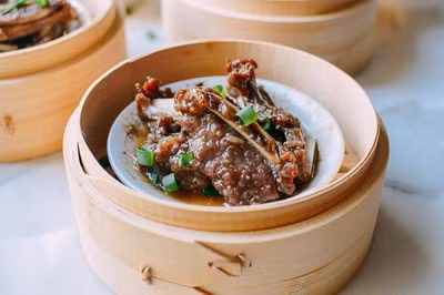 Lấy sườn ra, rắc hành lá lên trên và dùng nóng.