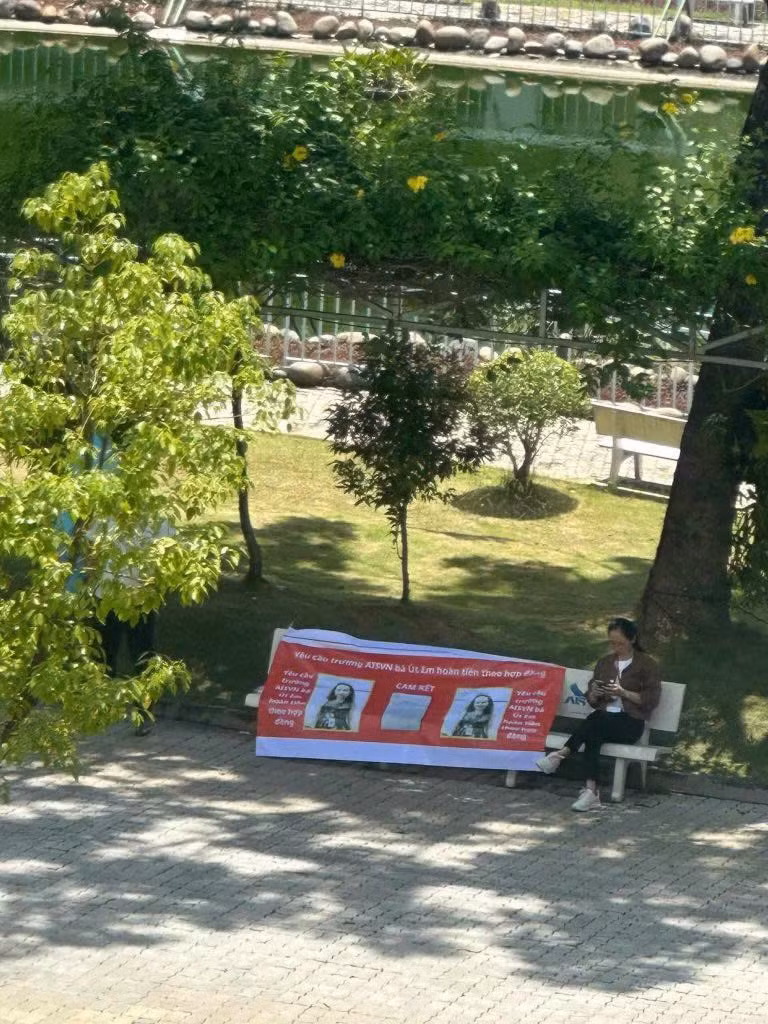 Một phụ huynh mang băng rôn đến trước cổng trường, bám trụ tại ghế đá để đòi nợ. Một phụ huynh mang băng rôn đến trước cổng trường, bám trụ tại ghế đá để đòi nợ.
