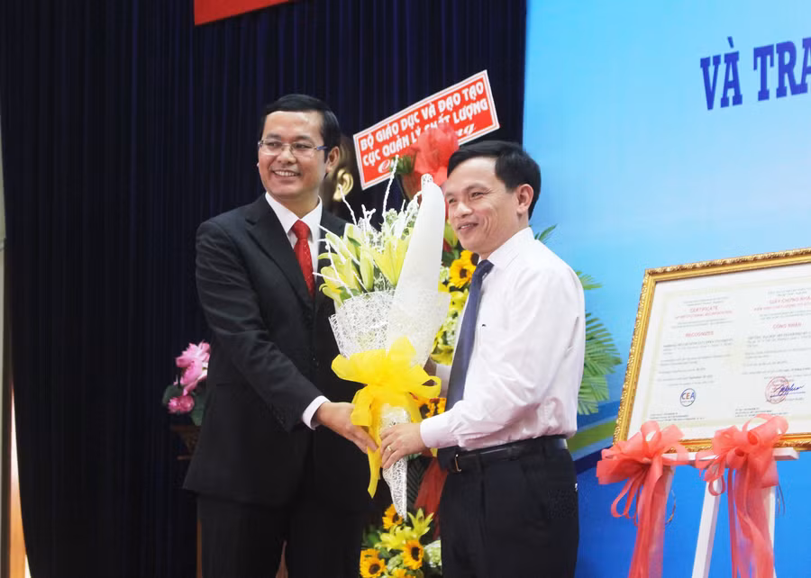 Ông Mai văn Trinh- Cục trưởng cục quản lý chất lượng Bộ GD&ĐT(bên phải) trao hoa chúc mừng nhà trường