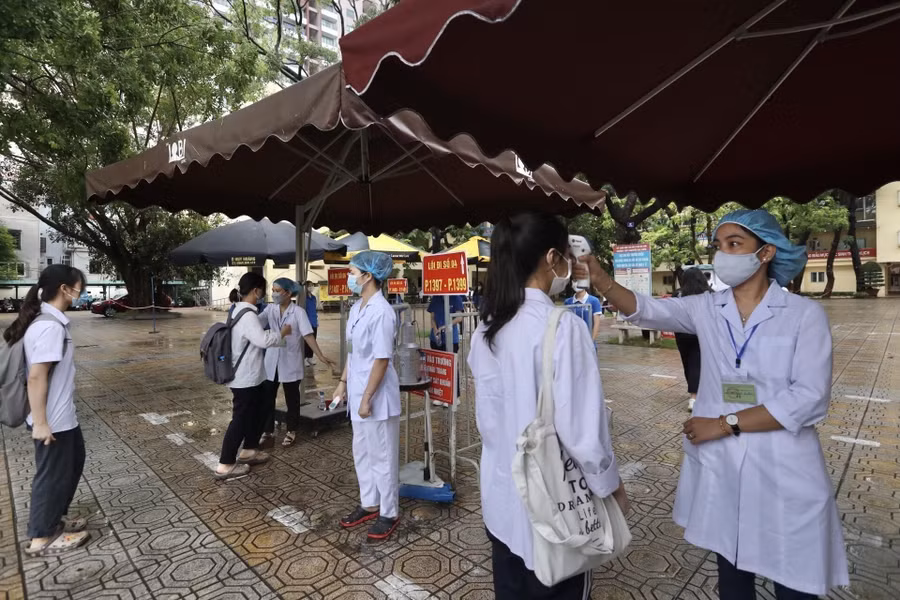 Lực lượng y tế tiến hành đo thân nhiệt cho thí sinh trước khi vào phòng thi