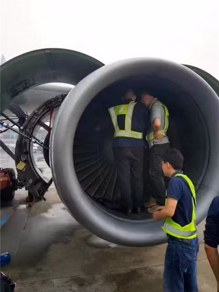  Các nhân viên kỹ thuật đang tìm kiếm những đồng xu mà bà Qiu đã vứt vào động cơ máy bay 