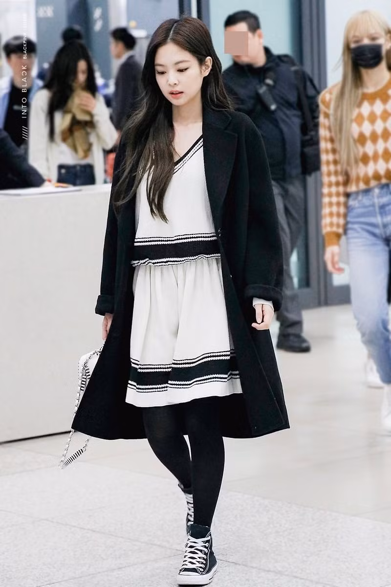 Trong set đồ này Jennie lại thiên về vẻ dịu dàng nữ tính cùng một bộ váy liền trắng cùng sneaker và áo dạ măng - tô dài màu đen