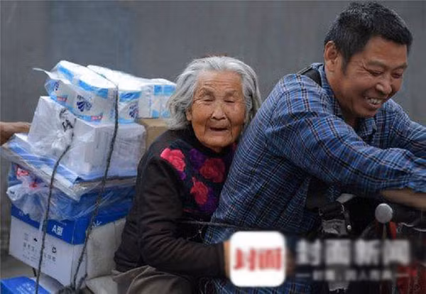 Nhân viên giao hàng đưa mẹ già mất trí nhớ đi làm cùng mỗi ngày ảnh 1 Ông Cai chở mẹ ngồi giữa đi giao hàng cùng mình khắp mọi ngõ ngách ở Thành Đô. Ảnh: The Cover.