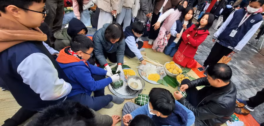 Cha mẹ và học sinh cùng gói bánh chưng Tết gửi tới người nghèo. Cha mẹ và học sinh cùng gói bánh chưng Tết gửi tới người nghèo.