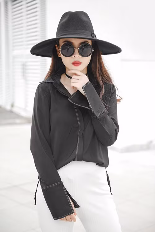 Yến Trang lại chọn sơ mi tay loe tông đen để phối cùng quần Tây trắng, mũ fedora và kính gương tròn sành điệu. dien-so-mi-chat-nhu-sao-viet-2