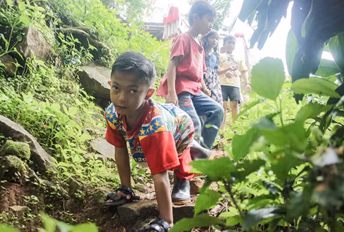 Mukhlis Abdul Holik bò đến trường bằng tay hàng ngày. Ảnh: AFP. Mukhlis Abdul Holik bò đến trường bằng tay hàng ngày. Ảnh: AFP