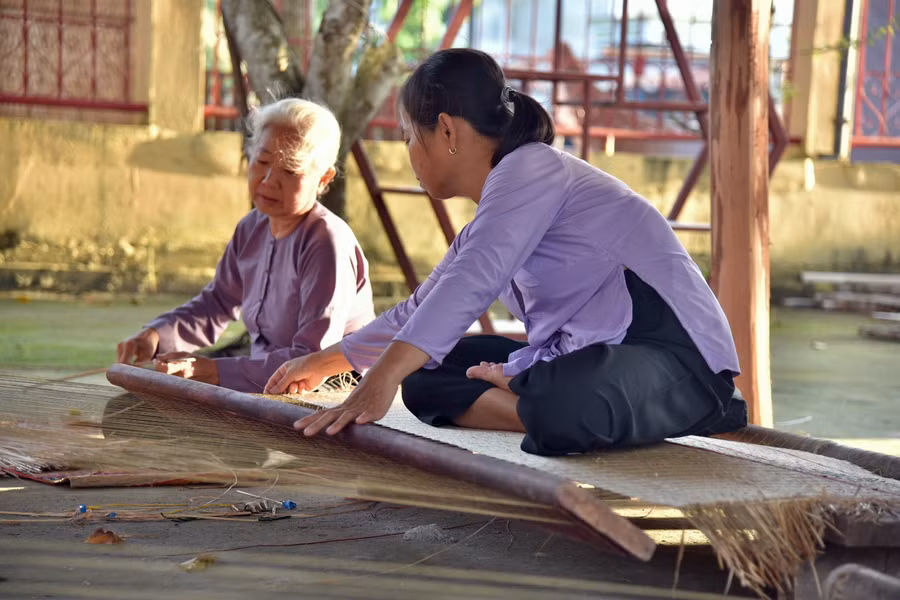 Bà Nguyễn Thị Vân cùng con gái dệt chiếu thủ công tại Đình Định Yên trước giờ diễn ra show thực cảnh.