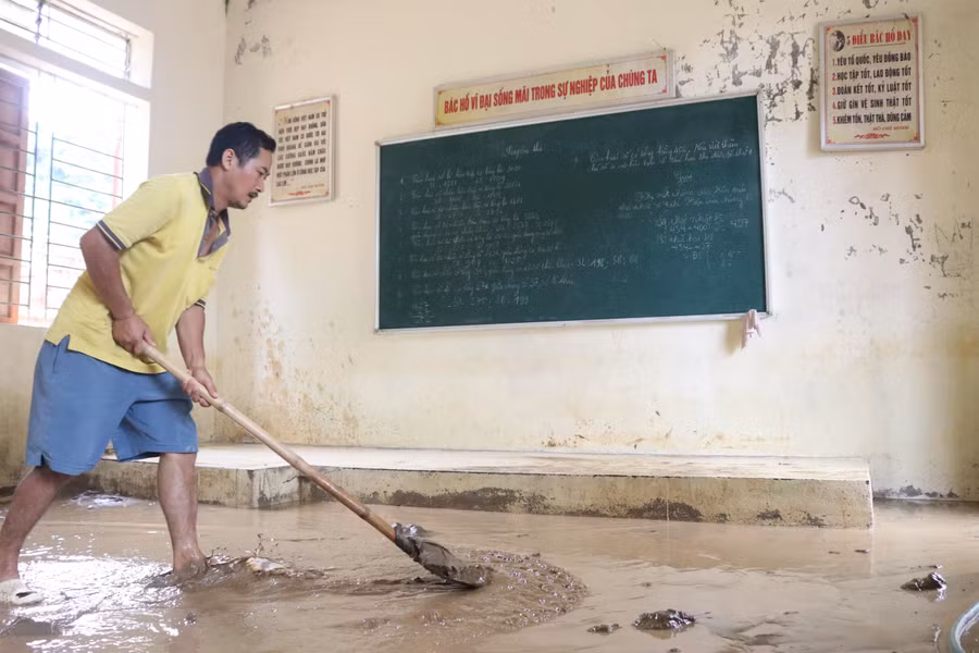 Người dân giúp nhà trường cào bùn đất ra khỏi lớp học.