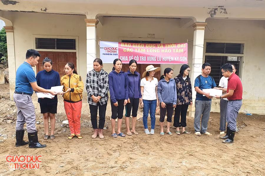 Phóng viên Báo Giáo dục và Thời đại trao quà cho các giáo viên bị lũ cuốn trôi nhà cửa.