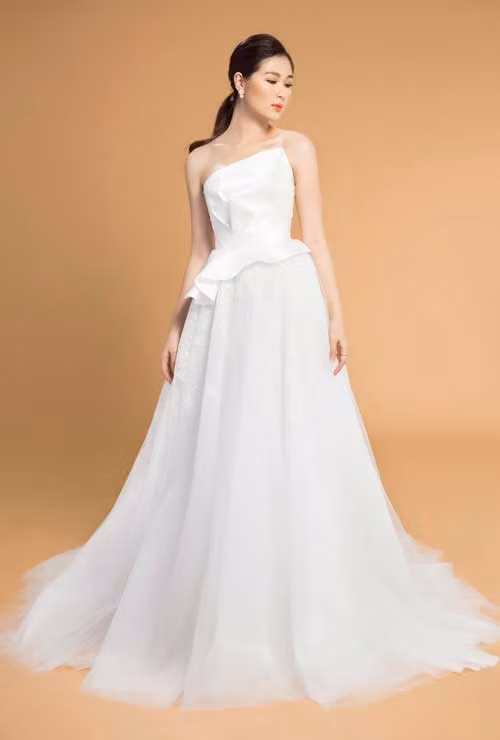 Váy cưới chữ A: Không quá khó để lý giải vì sao kiểu dáng váy này luôn nằm trong danh sách best seller của các nhà mốt bởi tính ứng dụng cao. Với thiết kế ôm sát phần thân áo,xòe nhẹ từ eo trở xuống, váy cưới chữ A phù hợp với mọi cô dâu, đặc biệt là các cô dâu mũm mĩm vì nó có thể che được khuyến điểm vòng 2, vòng 3 và kéo dài thân một cách tự nhiên.