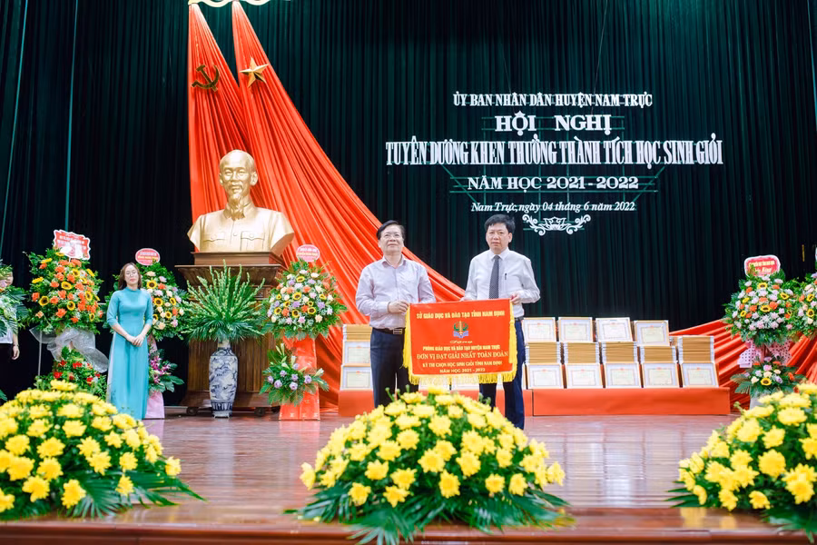 Giám đốc Sở GD&amp;ĐT Cao Xuân Hùng (bìa trái) trao tặng cờ Đơn vị đạt giải Nhất toàn đoàn Kỳ thi chọn học sinh giỏi tỉnh Nam Định năm học 2021-2022 cho Trưởng Phòng GD&amp;ĐT huyện Nam Trực Đoàn Quang Vụ (bìa phải).