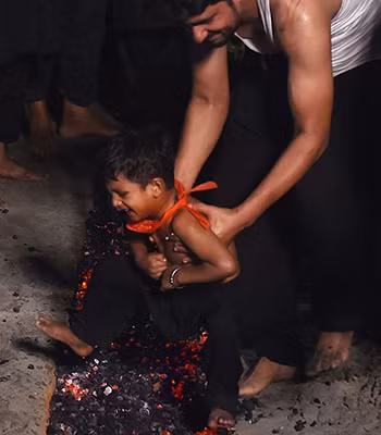 Một bé trai ở Lahore, Pakistan, sợ hãi khi bị bố đặt xuống đám than nóng trong lễ hội Ashura. Ảnh: AFP