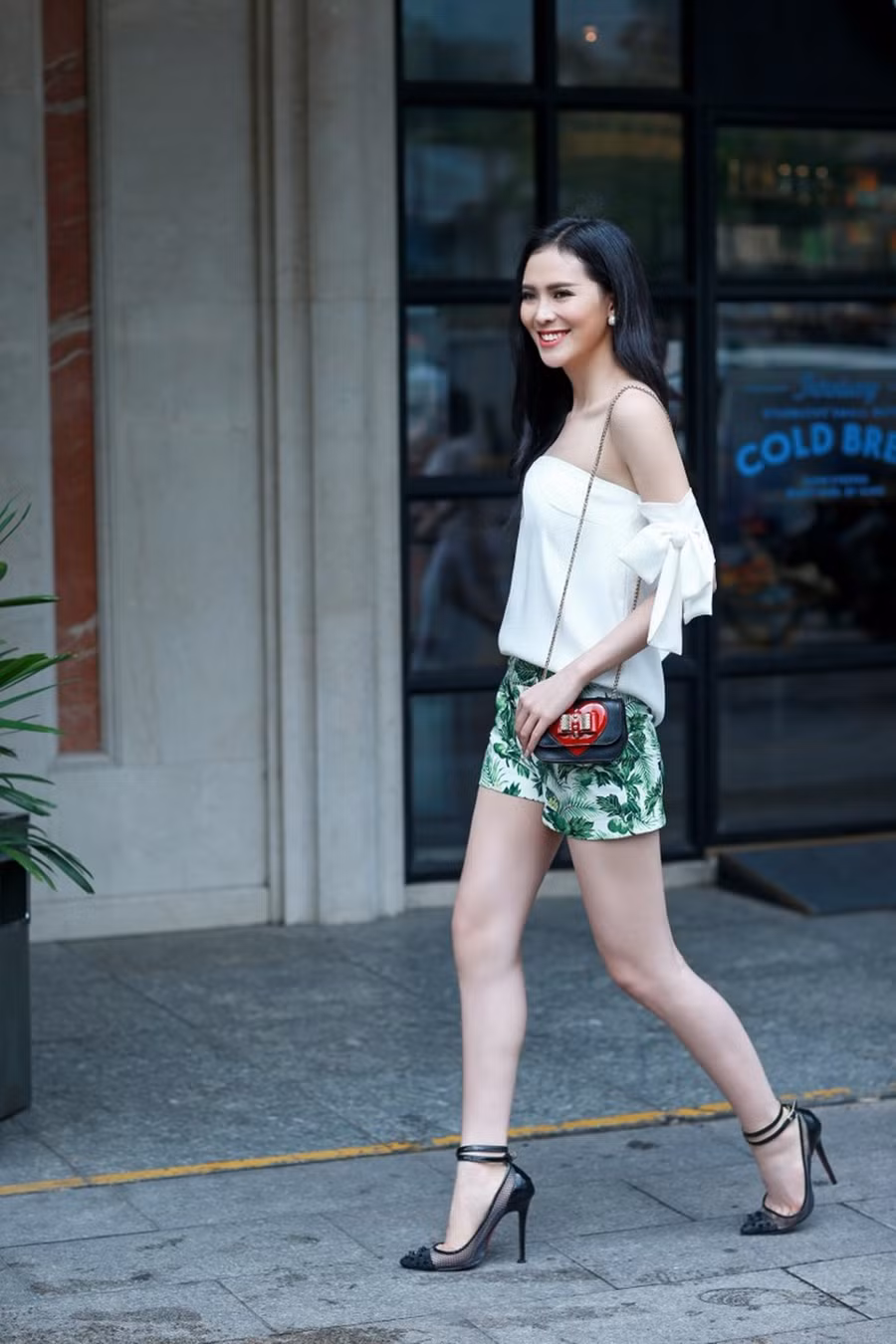 Áo trắng phom dáng rộng được mix khéo léo với quần short họa tiết lá cây cùng túi xách và giày mang đến nét mới mẻ đầy hiện đại.