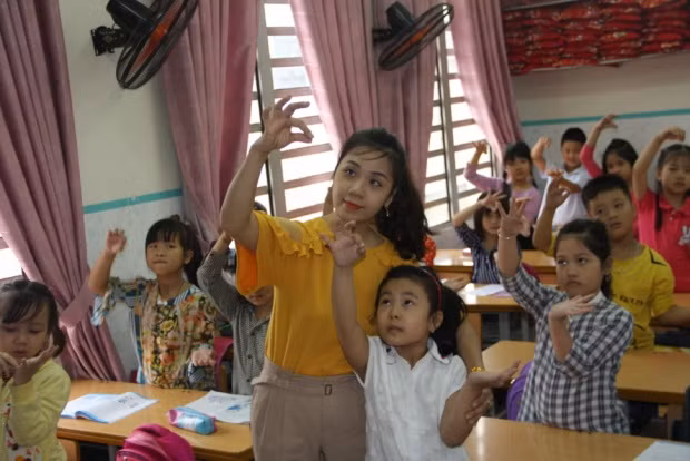 Giáo viên nắn nót từng cử chỉ, động tác cho học sinh khi hát Xoan. Ảnh: Trung Toàn