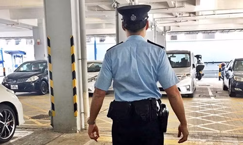Viên cảnh sát đội mũ ngược tại một bãi đỗ xe ở Hong Kong. Viên cảnh sát đội mũ ngược tại một bãi đỗ xe ở Hong Kong. Ảnh: South China Morning Post.