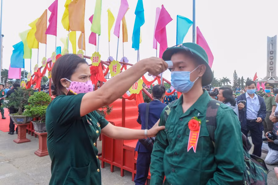 Cán bộ Quân y kiểm tra thân nhiệt cho thanh niên trước khi lên xe về với đơn vị đóng quân.