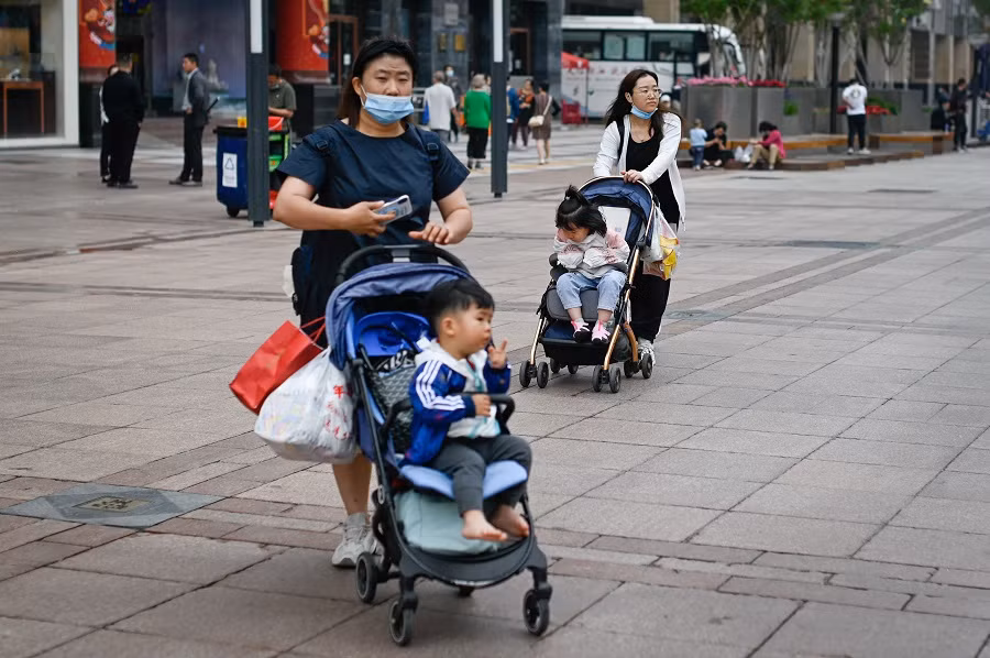Hai người phụ nữ đẩy xe nôi dọc theo một con phố kinh doanh ở Bắc Kinh, Trung Quốc. (Ảnh: Wang Zhao/AFP). Hai người phụ nữ đẩy xe nôi dọc theo một con phố kinh doanh ở Bắc Kinh, Trung Quốc. (Ảnh: Wang Zhao/AFP).
