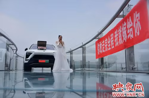 Ngày 15/8, tại cầu kính Fuxi Mountain Skywalk (nằm ở núi Phục Hy, Hà Nam), một cô gái đã thử thách người bạn trai sợ độ cao của mình. Cô mặc váy cưới, đứng trên cầu cùng chiếc xe ôtô mới cứng và một vali tiền trên mui xe. Cạnh cô là băng rôn:"Em sẽ kết hôn với anh nếu anh dám bước tới bên em". Ngày 15/8, tại cầu kính Fuxi Mountain Skywalk (nằm ở núi Phục Hy, Hà Nam), một cô gái đã thử thách người bạn trai sợ độ cao của mình. Cô mặc váy cưới, đứng trên cầu cùng chiếc xe ôtô mới cứng và một vali tiền trên mui xe. Cạnh cô là băng rôn:Em sẽ kết hôn với anh nếu anh dám bước tới bên em.
