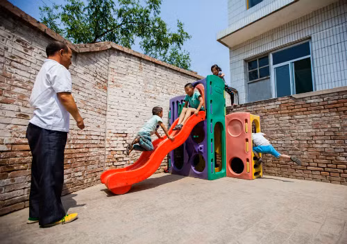 Chen ngắm học sinh chơi đùa ở sân trường. Ảnh:China Daily Chen ngắm học sinh chơi đùa ở sân trường. Ảnh: China Daily