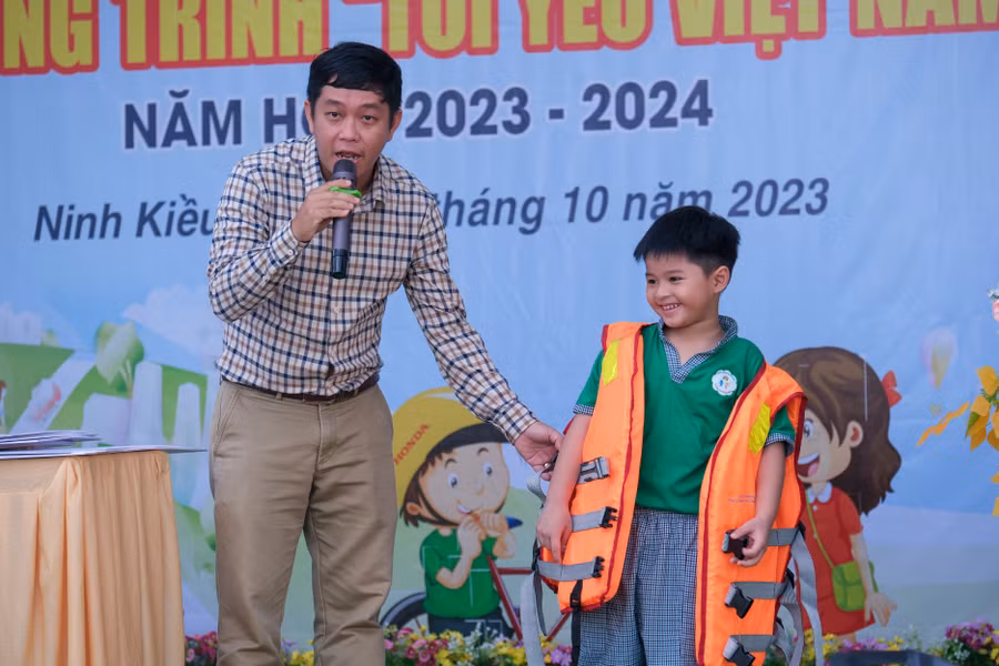 Ông Lê Tuấn Khải, chuyên viên Văn phòng Ban ATGT TP Cần Thơ hướng dẫn mặc áo phao và sử dụng dụng cụ nổi cứu sinh cầm tay cho trẻ khi tham gia giao thông bằng đường thủy.