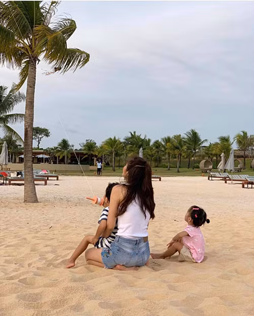 Hà Tăng ngồi bên bờ biển cùng hai con chơi thả diều trong kỳ nghỉ ở Phú Quốc.