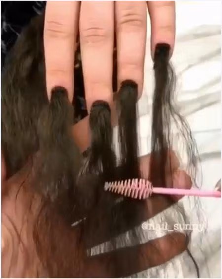Người thợ dùng chổi mascara chải tóc trên móng