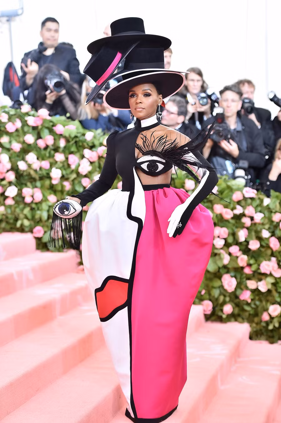 Chiếc váy của Janelle Monae có một đôi mắt được tô điểm bên ngực trái. Cô đội trên đầu 4 chiếc mũ xếp chồng lên nhau.