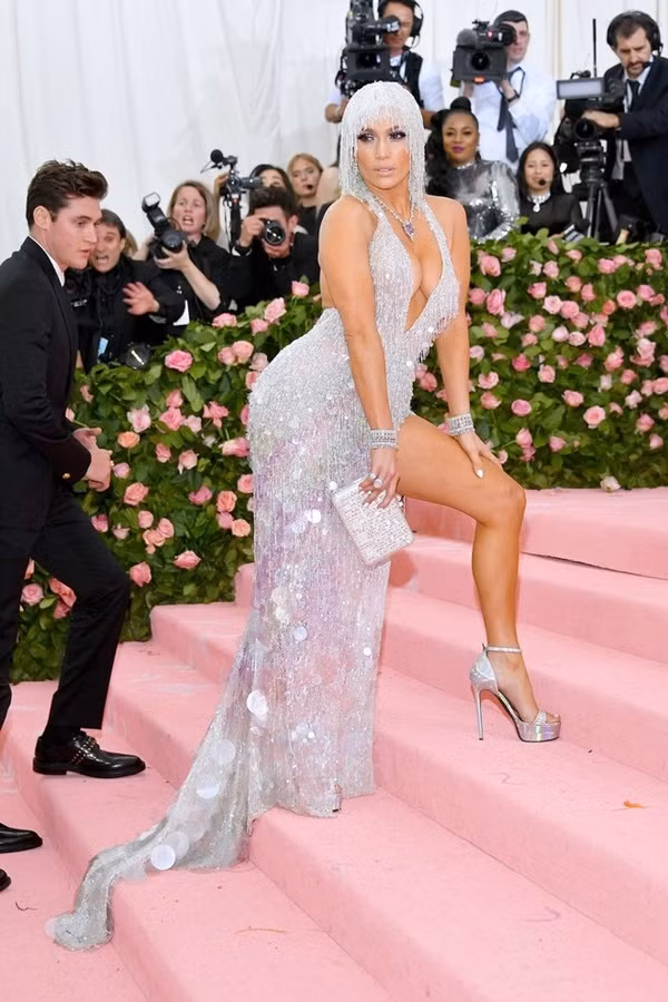 Jennifer Lopez chọn đầm kim sa ánh bạc xẻ ngực sâu và mũ đính cườm.