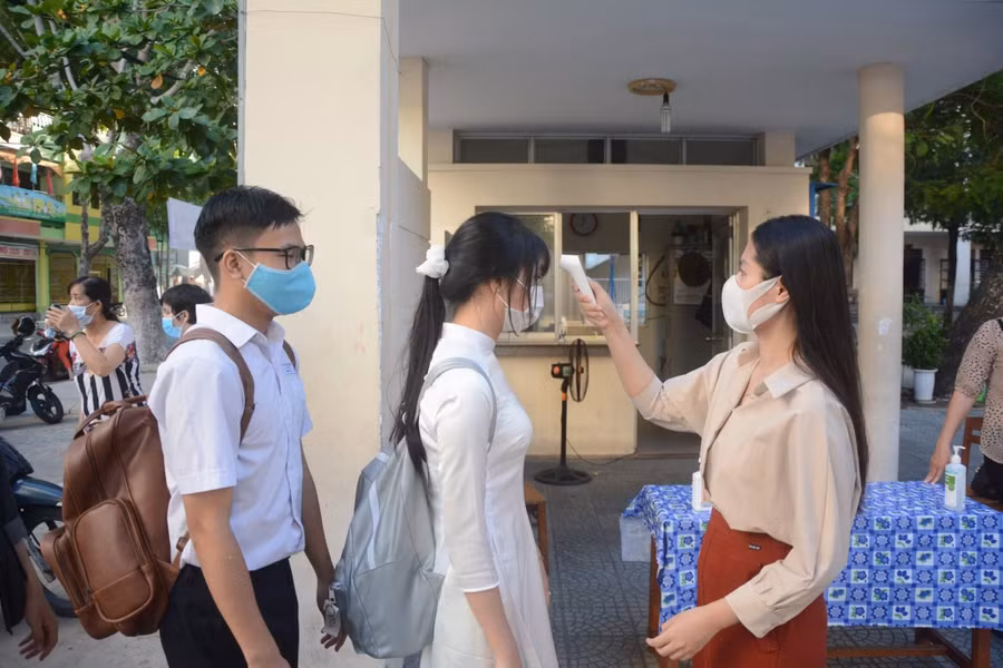 Giáo viên đo thân nhiệt cho học sinh tại trường THPT Trần Phú (TP Đà Nẵng).