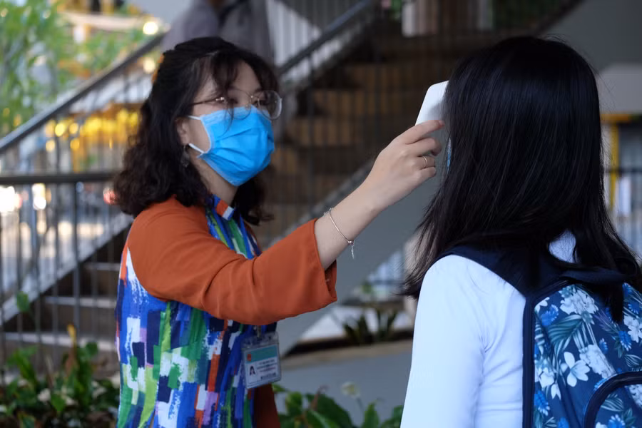 Đo thân nhiệt cho các em học sinh trước khi vào lớp học.