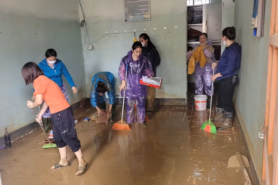 Giáo viên ở huyện Quỳ Châu đang cào bùn ra khỏi phòng học. (Ảnh: Phạm Tâm)