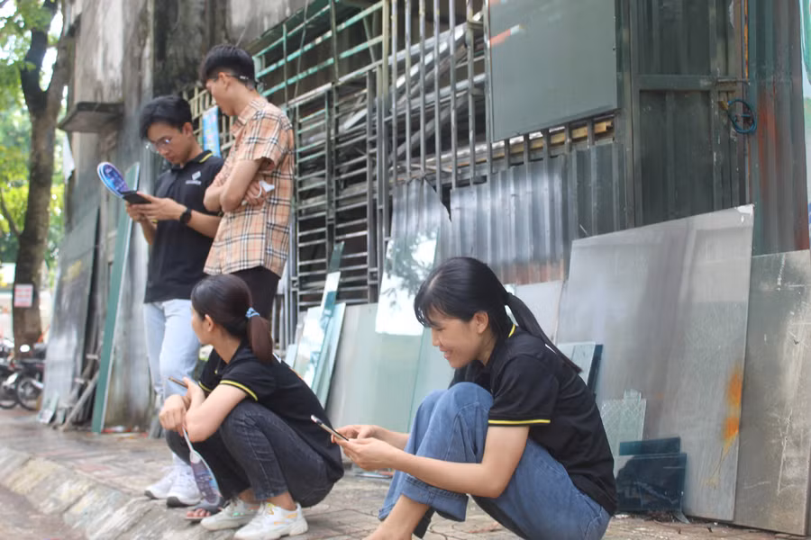 Chị Trịnh Thị Hương (bìa phải) ngồi vạ vật đợi con ngoài điểm thi Trường THPT Tô Hiến Thành (TP Thanh Hóa). Ảnh: Lường Toán.